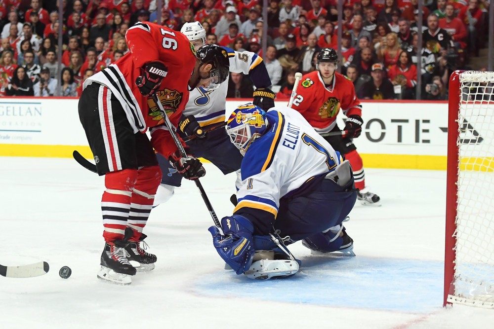 St. Louis Blues Goalie Brian Elliott  battles with Chicago Blackhawks Left Wing Andrew Ladd  to block a shot in the first period of action during the Game three of the first round of the NHL Playoffs between the Chicago Blackhawks and