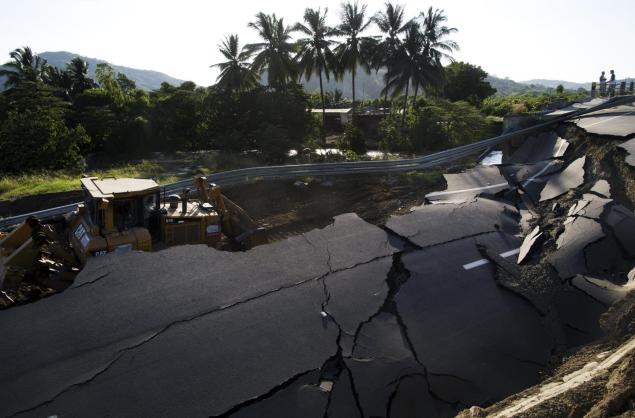 A bulldozer works to clear a section of highway that collapsed in a massive earthquake in the outskirts of Portoviejo Ecuador