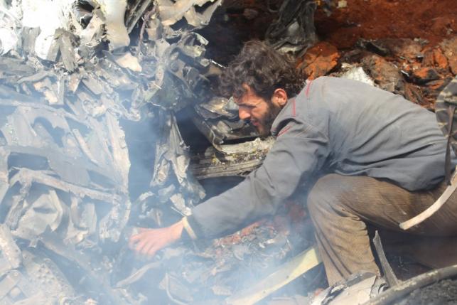 A man inspects the wreckage of a Syrian warplane that was shot down in the Talat al Iss area south of Aleppo Syria