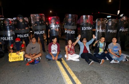 Demonstrators sit in front of a line of police in riot gear outside Republican U.S. presidential candidate Donald Trump's campaign rally in Costa Mesa California