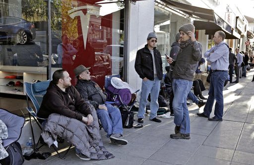 Nick Tobin left with his father Byron Tobin second from left wait in line to be the first to sign a wait list to own the new Tesla Model 3 at the Tesla showroom in Pasadena Calif. Thursday