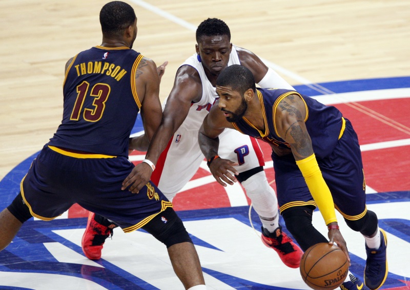 Cleveland Cavaliers&#039 guard Kyrie Irving comes off a screen set by Tristan Thompson as Detroit Pistons&#039 guard Reggie Jackson fights over