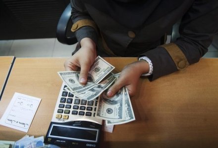 A currency exchange dealer counts U.S. dollar banknotes for a client at a shop in northern Tehran in this file