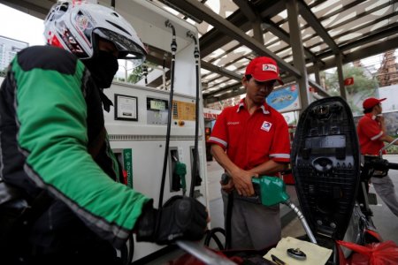 An employee at a Total fuel station fills up a motorcycle in south Jakarta