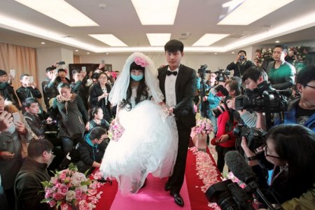 Newly-wed bride Fan Huixiang a 25-year-old cancer patient wearing a mask walks on the red carpet with her groom Yu Haining during their wedding at a hospital in Zhengzhou Henan province