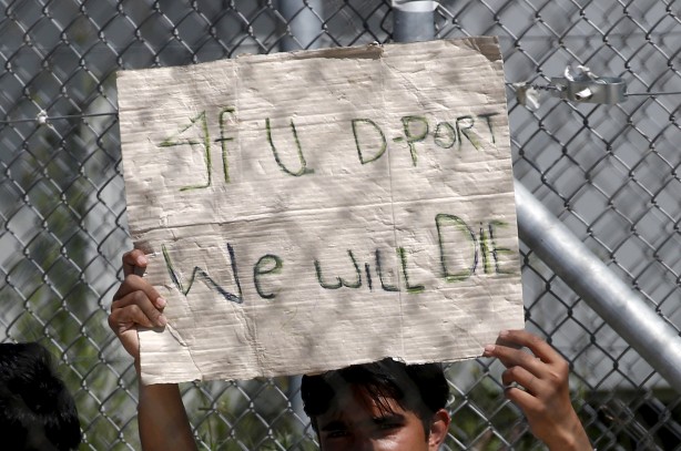 A migrant who will be returned to Turkey holds a placard during a demonstration inside the Moria registration centre on the Greek island of Lesbos