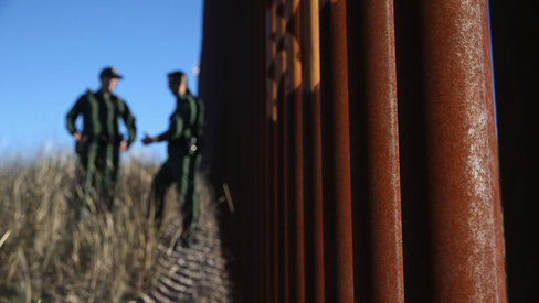 U.S. Border Patrol agents talk next to the U.S.-Mexico border fence on Dec. 9 2014 near Nogales Arizona