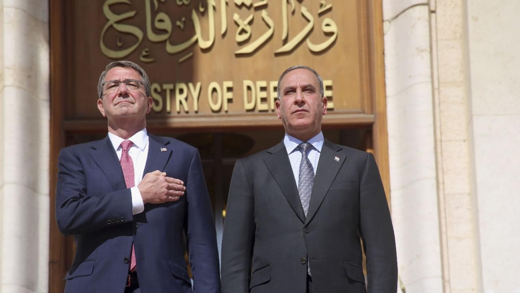 U.S. Defense Secretary Ash Carter his Iraqi counterpart Khaled al Obeidi stand for their countrys national anthems at the Ministry of Defense Baghdad Iraq Mon