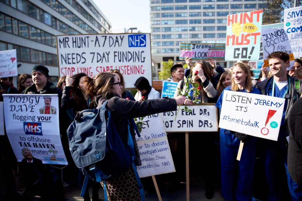 A woman offers roses to junior doctors holding placards as they take part in the start of a 48-hour strike on their picket line outside St Thomas&#039 Hospital in London Tuesday