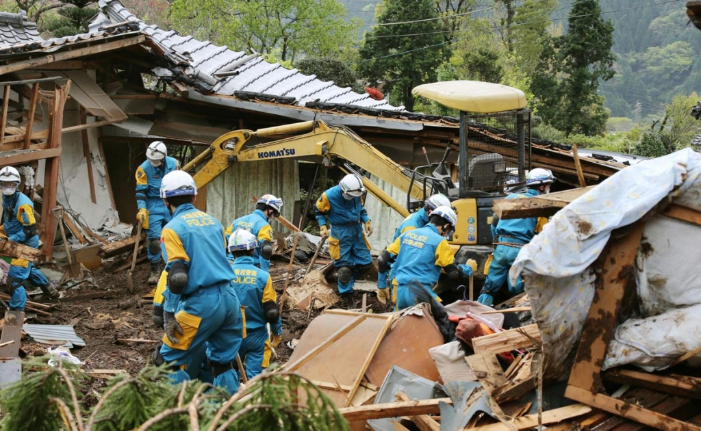 Police officers search for missing persons near houses destroyed by landslide in Minamiaso Kumamoto prefecture Japan Sunday