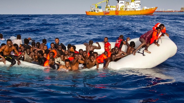 Refugees ask for help from a dinghy boat as they are approached by the SOS Mediterranee's ship Aquarius on Sunday. The UNHCR said up to 500 people are feared dead in the sinking