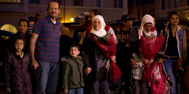 Loading Several refugees hold their children close as they arrive in Rome after flying in from Greece to Italy with the Pope