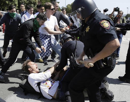 Police officers take a man into custody who was protesting Republican presidential candidate Donald Trump outside of the Hyatt Regency hotel during the California Republican Party 2016 Convention in Burlingame Calif. Friday