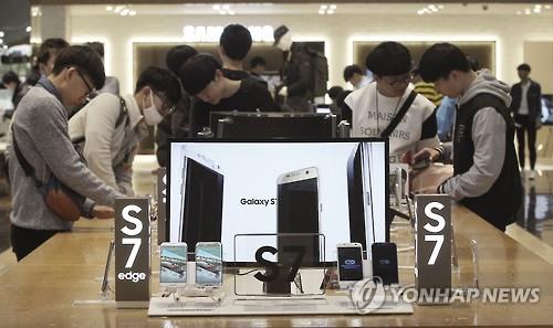 Visitors look at Galaxy S7 smartphones at a shop in Seoul