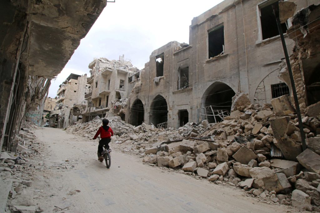 A boy rides a bicycle near damaged buildings in the rebel held area of Old Aleppo Syria