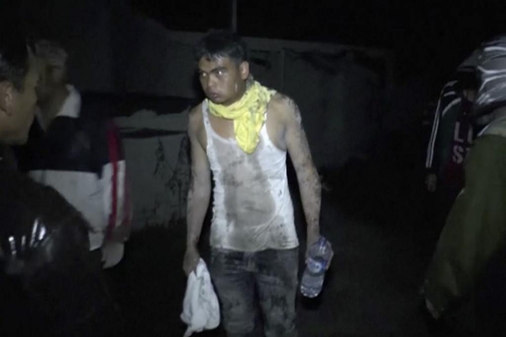 A man covered in dust leads rescuers after an eruption of Mount Sinabung in Tanah Karo North Sumatra Indonesia Saturday