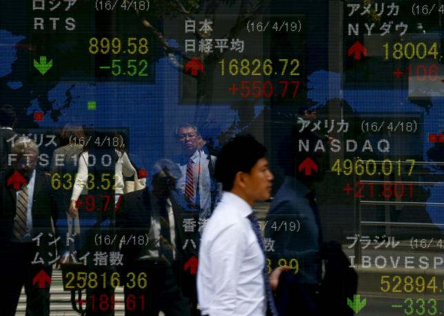 A man walks past a display of the Nikkei average and other market indices outside a brokerage in Tokyo Japan