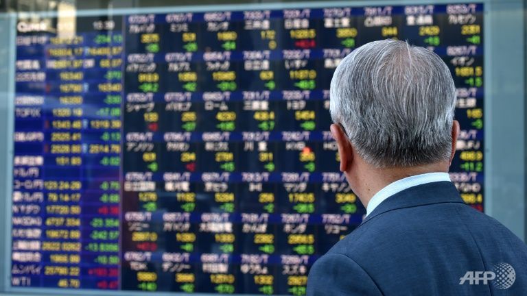 A pedestrian looks at a quotation board flashing the Nikkei key index from the Tokyo Stock Exchange in Tokyo