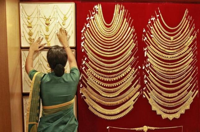 A saleswoman arranges a gold necklace inside a jewellery showroom in Kochi