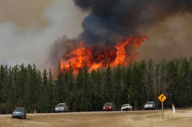 A wildfire burns as evacuees who were stranded north of Fort McMurray Alberta Canada head south of Fort Mc Murray on Highway 63