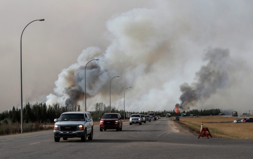 A group of evacuees in a convoy drive in front of smoke from the the wildfires near Fort McMurray Alberta Canada