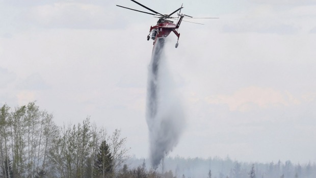 A helicopter drops water while fighting the wildfire