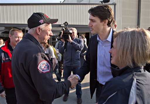 Prime Minister Justin Trudeau shakes hands with Fort Mc Murray fire chief Darby Allen as Alberta Premier Rachel Notley right looks on in Edmonton Friday