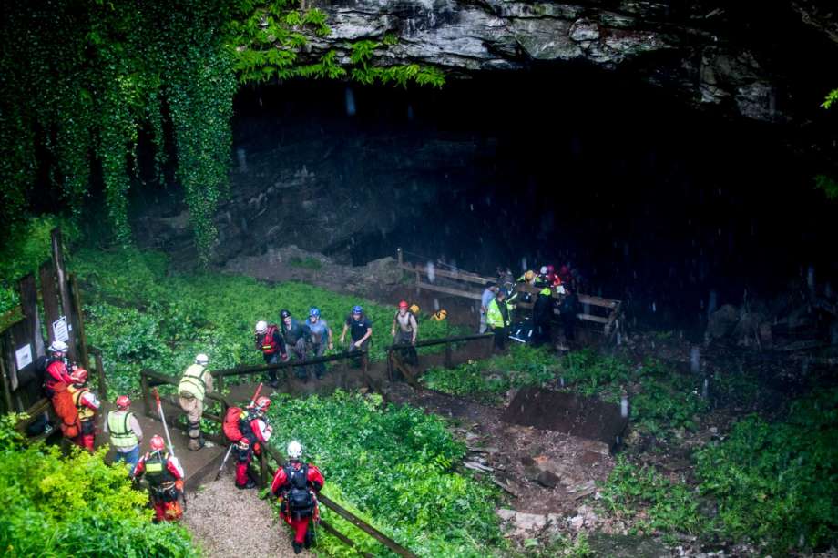 Rescued people walk out of the entrance to Hidden River Cave after officials said over a dozen people who exploring the cave were trapped by rising water Thursday