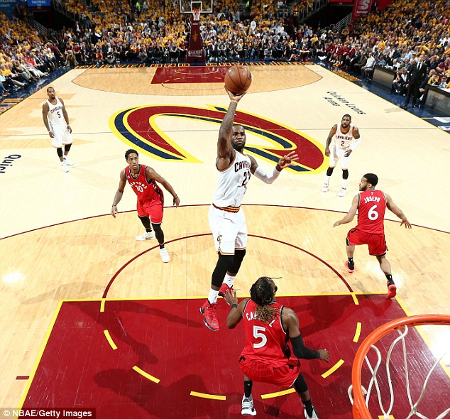 Cleveland Cavaliers star Le Bron James shoots as De Marre Carroll watches on from under the hoop