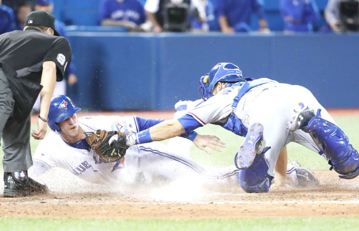 Michael Saunders of the Toronto Blue Jays is thrown out at home plate in the eighth inning Brett Nicholas of the Texas Rangers tags him out in Toronto Canada Monday. — AFP