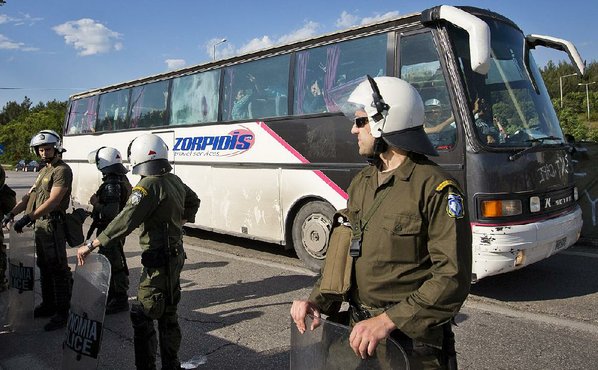 DARKO BANDIC							Credit AP				Greek police secure the passage of a bus carrying migrants evacuated from a makeshift camp in Idomeni Greece on Tuesday