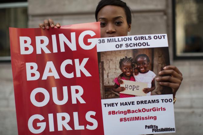 469699542-woman-holds-a-sign-as-other-protesters-gather-outside-1