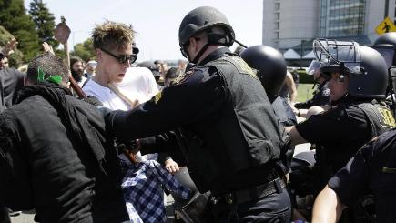 Police officers push back a group protesting against Republican presidential candidate Donald Trump outside of the Hyatt Regency hotel