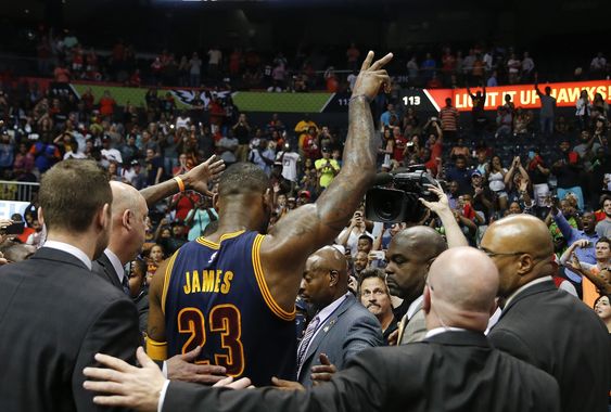 Le Bron James waves to the crowd as he is escorted off the court by security officials after defeating Atlanta Hawks in Game 4 of the second-round NBA basketball playoff series Sunday