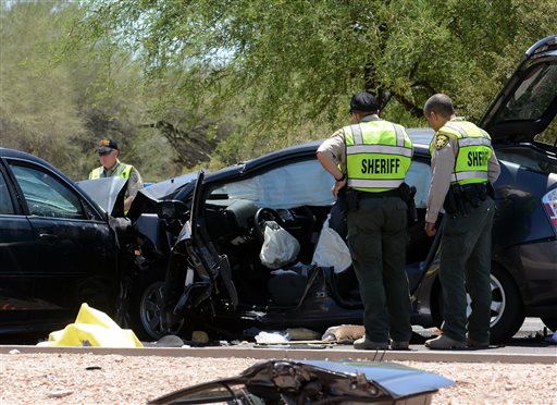 Pima County Sheriff's Department deputies examine a wrecked Toyota Prius at the scene of a fatal car crash on East Ina Road west of Westward Look Drive north of Tucson Ariz. on Saturday