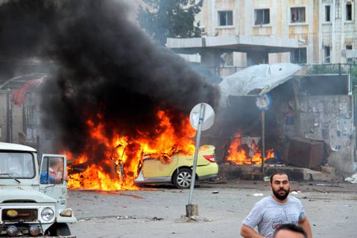 A car is left in flames at the scene where suicide bombers blew themselves up at a bus station during morning rush hour in the coastal town of Tartus Syria