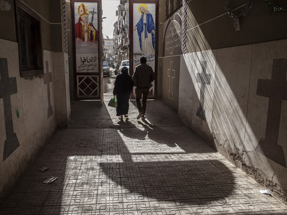 Coptic Christians walk outside St. Markos Church in Minya south of Cairo. Egypt's president has vowed that those responsible for stripping an elderly Christian woman and parading her naked on the streets wil