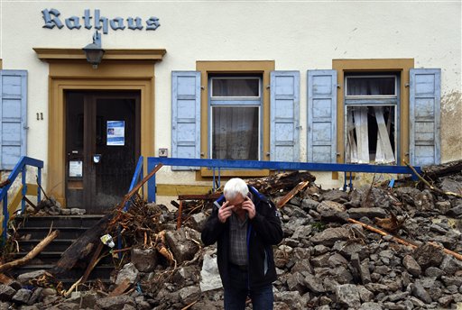 A man makes a phone call in front of an avalanche of debris that hit the town hall in Braunsbach Germany Monday