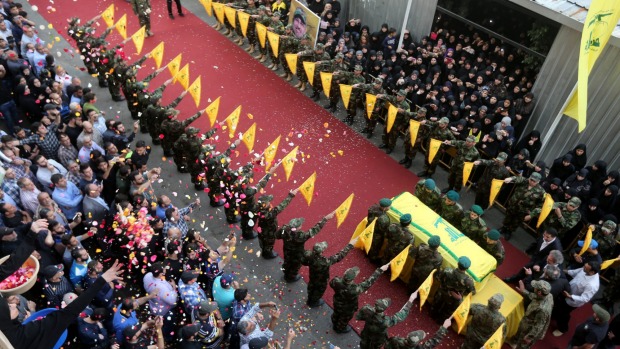 People toss rose petals near the coffin of top Hezbollah commander Mustafa Badreddine