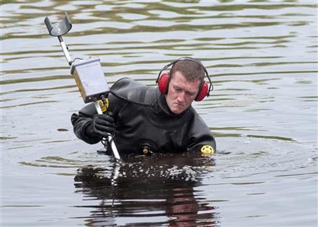 A Massachusetts State Police diver uses a metal detector to search Stoneville Pond near the site where Auburn police Officer Ronald Tarentino was fatally shot during a traffic stop in Auburn Mass. Sunday