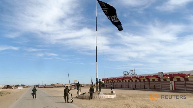 Iraqi security forces work on lowering the Islamic State flag west of Ramadi