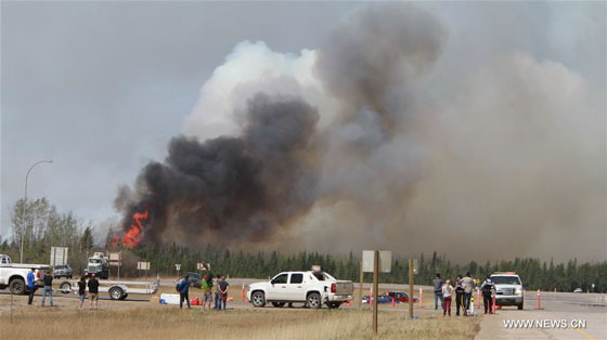 Journalists and policemen gather near the wildfire site in Alberta Province of Canada