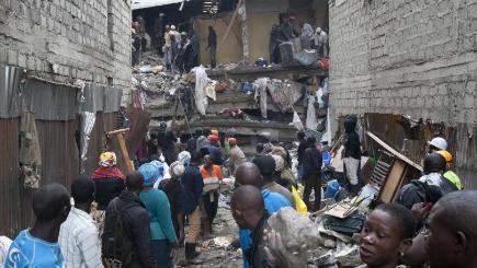 People help survivors retrieve their household items at the site of a building collapse in Nairobi Kenya