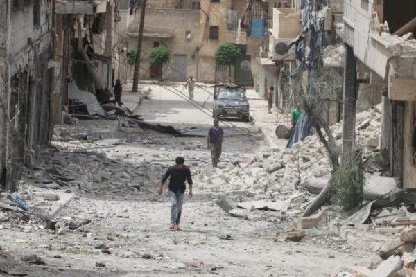 People walk on the rubble of damaged buildings after an airstrike in the rebel held area of Aleppo's Baedeen district Syria