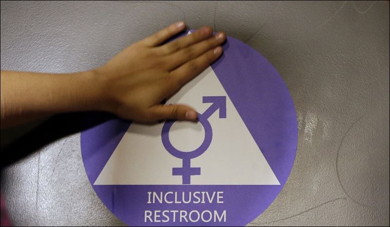 A new sticker is placed on the door at the ceremonial opening of a gender neutral bathroom at Nathan Hale High School in Seattle. Conservatives angered by the inclusion of LGBT protections in an otherwise routine spending bill scuttled the measure today