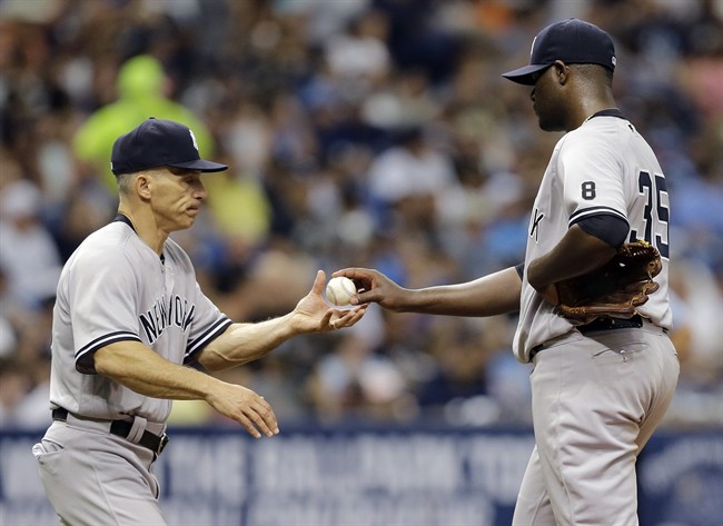 New York Yankees starting pitcher Michael Pineda right hands the baseball to manager Joe Girardi as he is taken out of the game against the Tampa Bay Rays during the fourth inning of a baseball game Saturday