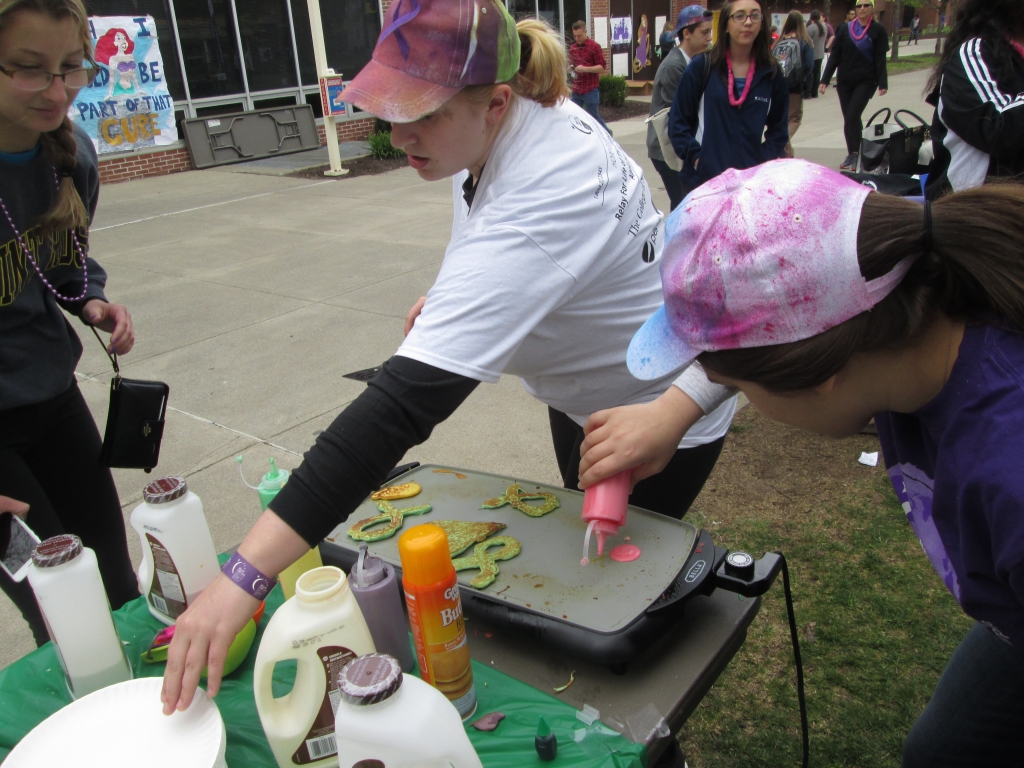 Maddy Schimmenti and Kristie Guerrero from Outside the Box cooking a pancake for customer Micheline Pasinella