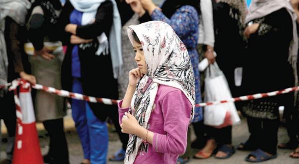 An immigrant child waiting for her turn to receive food aid close to Ellinikon International Airport in Athens on Tuesday