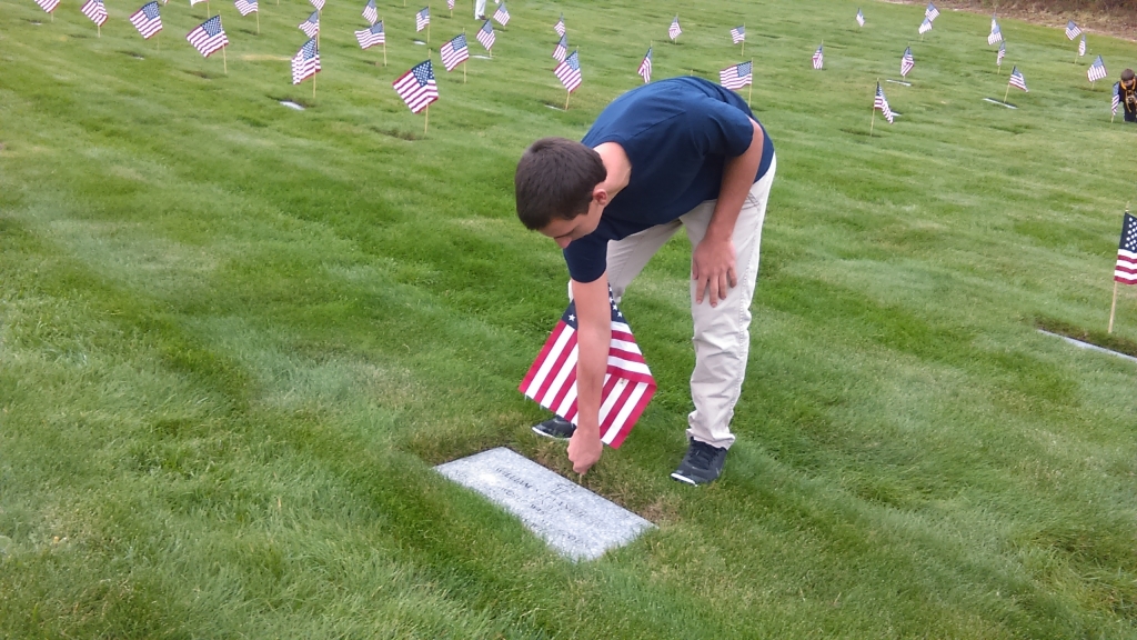 Monument Beach resident Scott Silva plants a flag on a veteran's gravesite