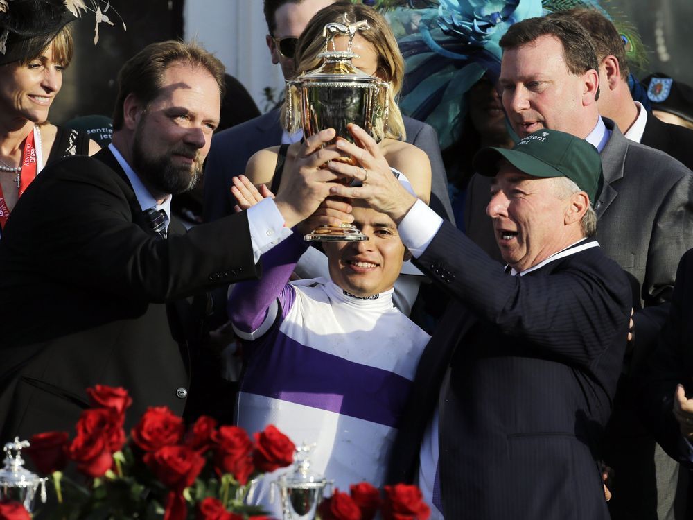 Mario Gutierrez middle trainer Doug O'Neill left and horse owner J. Paul Reddam of Windsor hold the trophy after Gutierrez rode Nyquist to victory in the 142nd running of the Kentucky Derby horse race at Churchill Downs Saturday